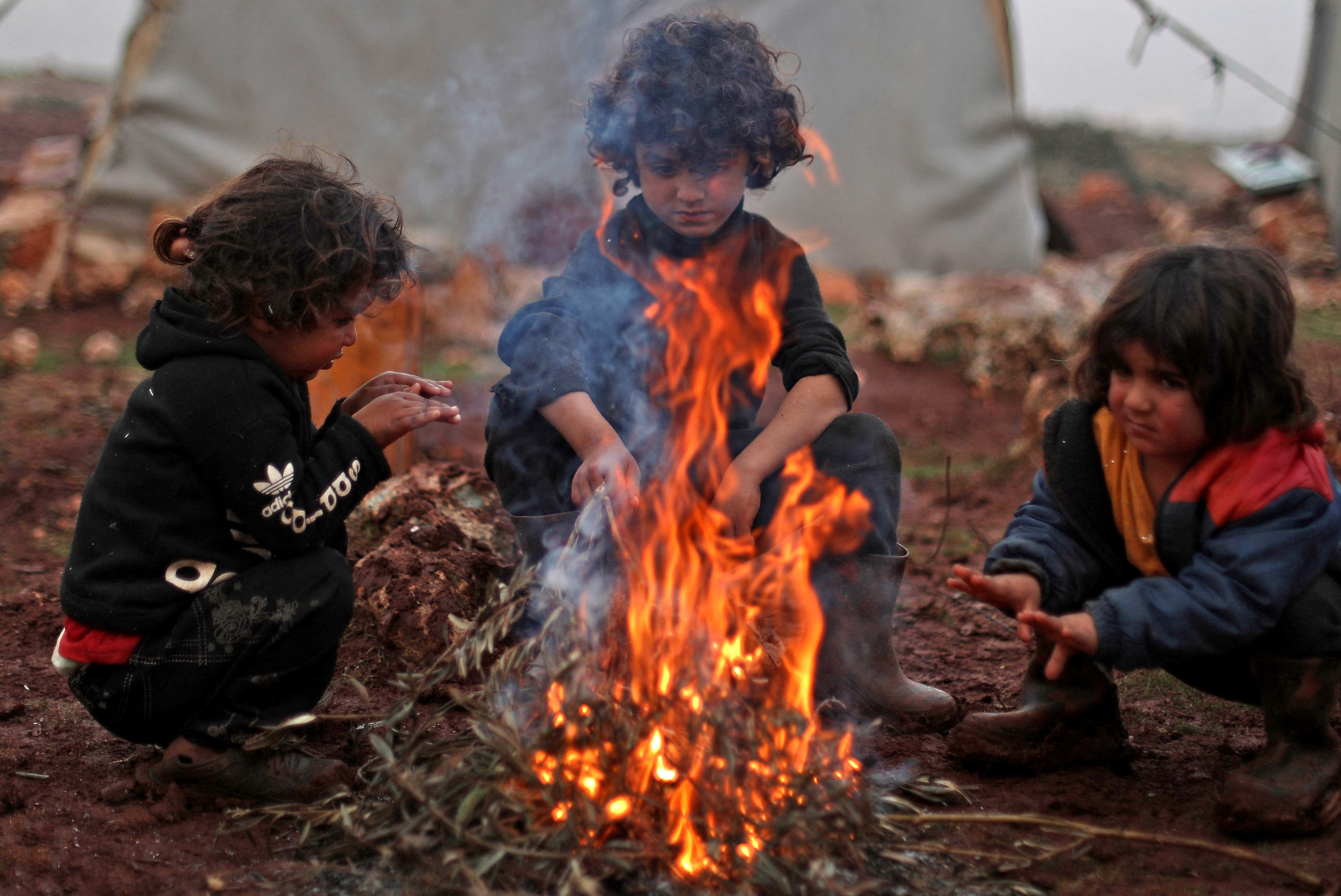 Børn får varmen omkring et bål